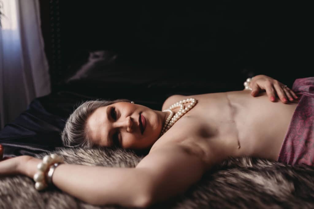 A boudoir portrait by professional photographers of a person reclining gracefully, adorned with pearls, showcasing a blend of classic elegance and modern allure.