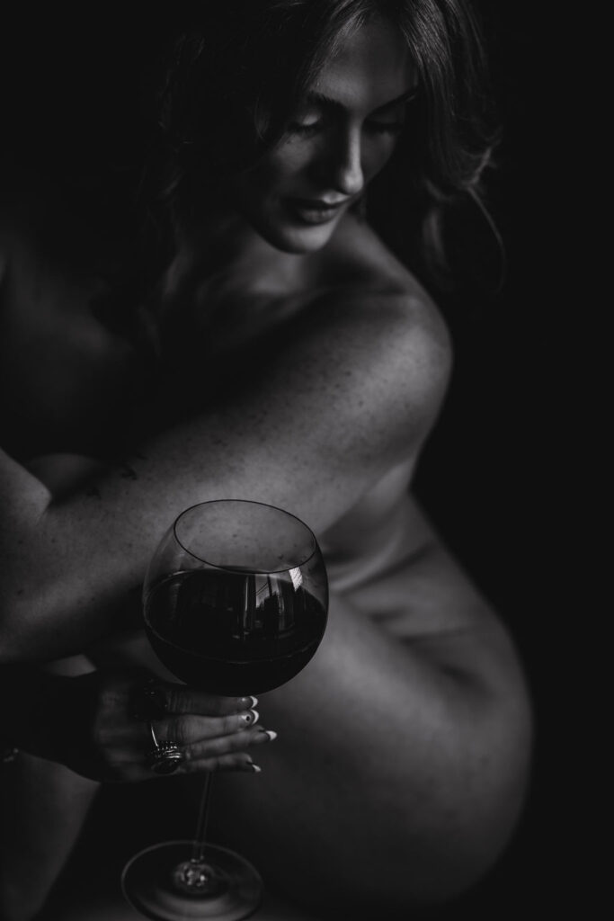 "Black and white branding photography of a woman holding a wine glass, showcasing bartending or beverage services with an intimate and elegant aesthetic.